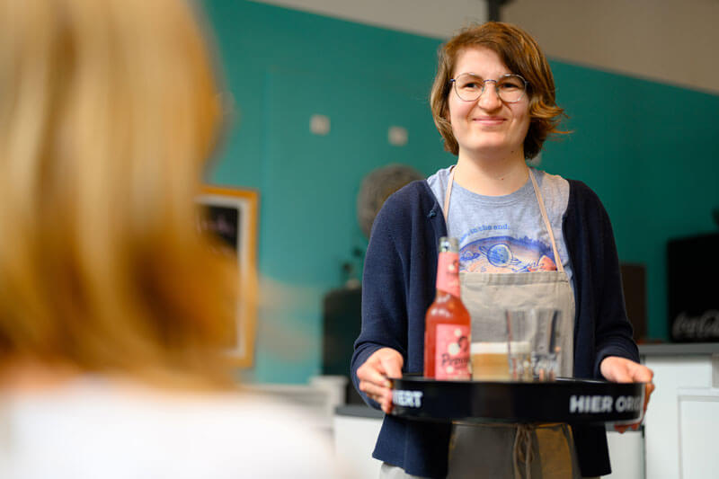 Café Homborner Werkstatt, Servicekraft serviert Getränke auf einem Tablett